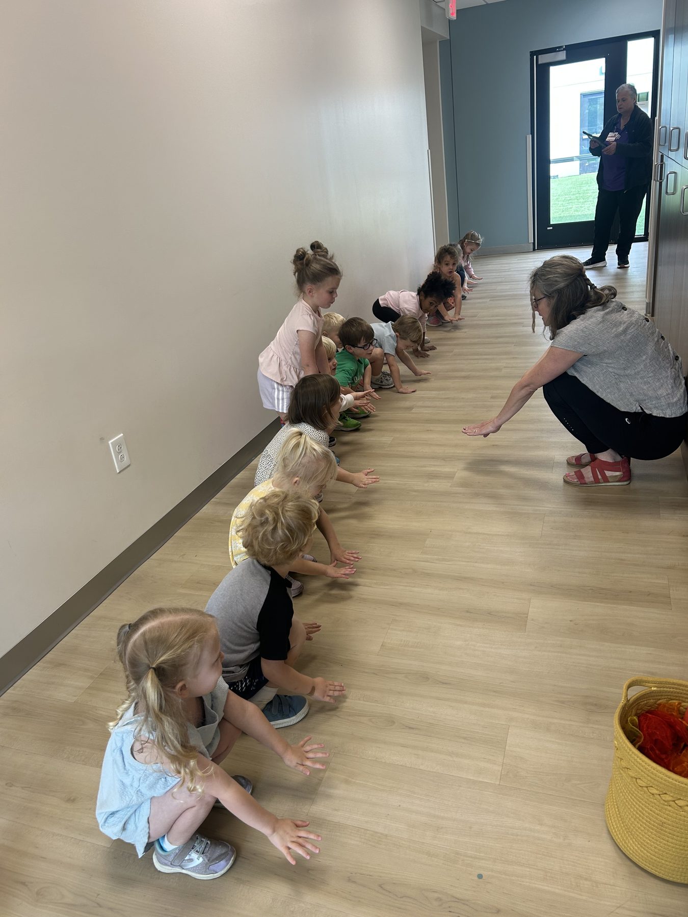 A Sun Dog Yoga teacher guiding a line of young children through a movement activity