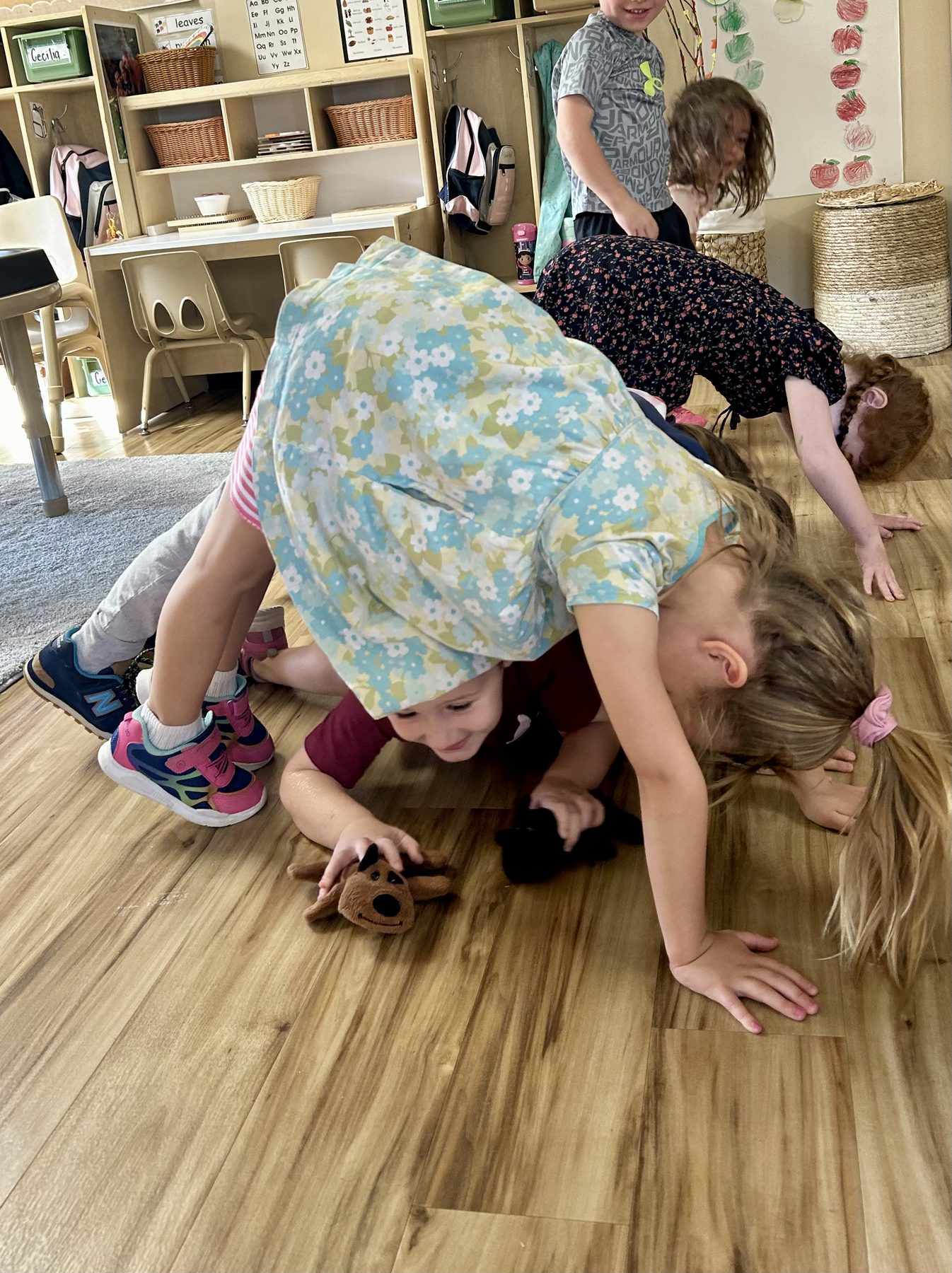 Children exploring a playful group yoga pose in a classroom
