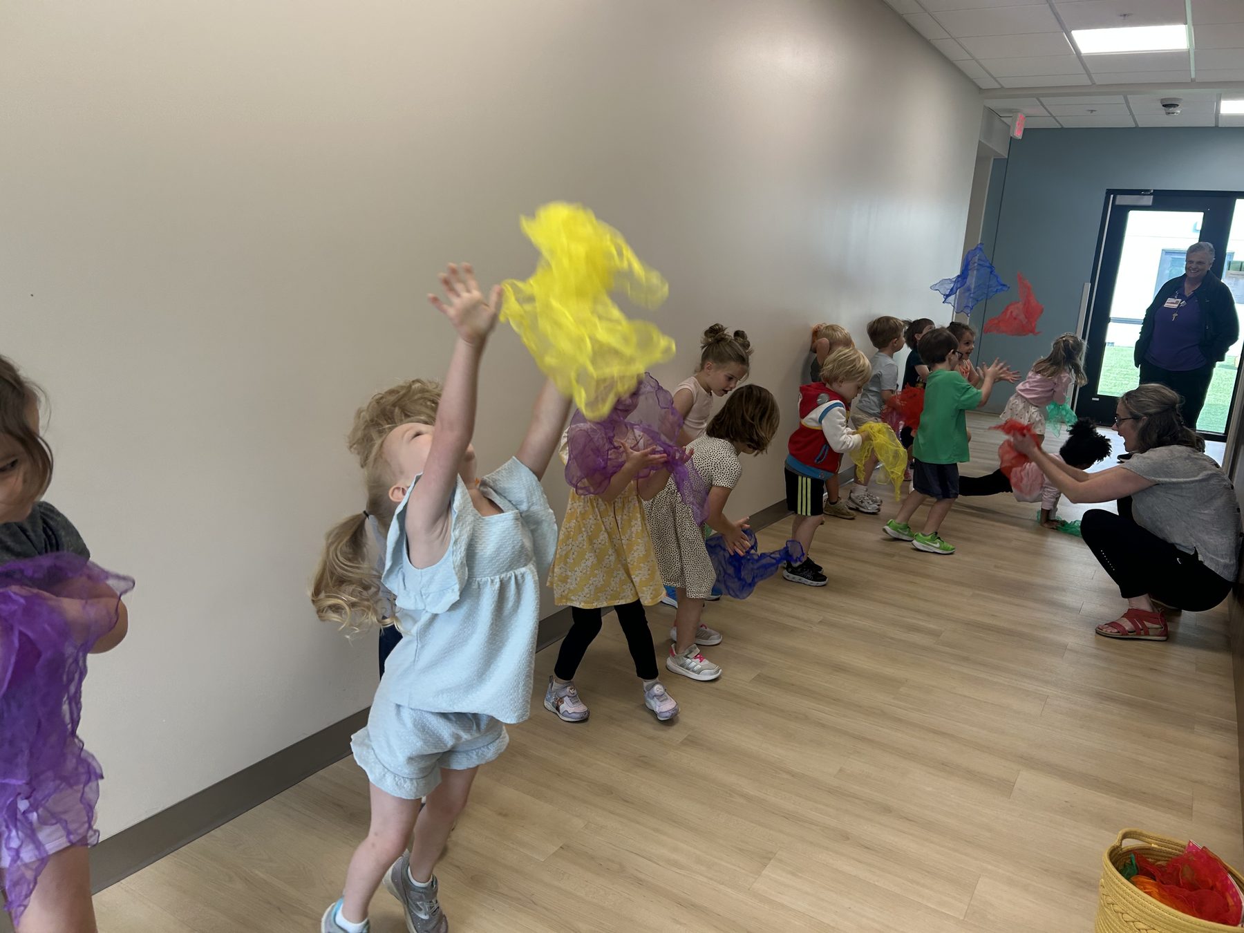 Children moving with colorful scarves during a Sun Dog Yoga activity