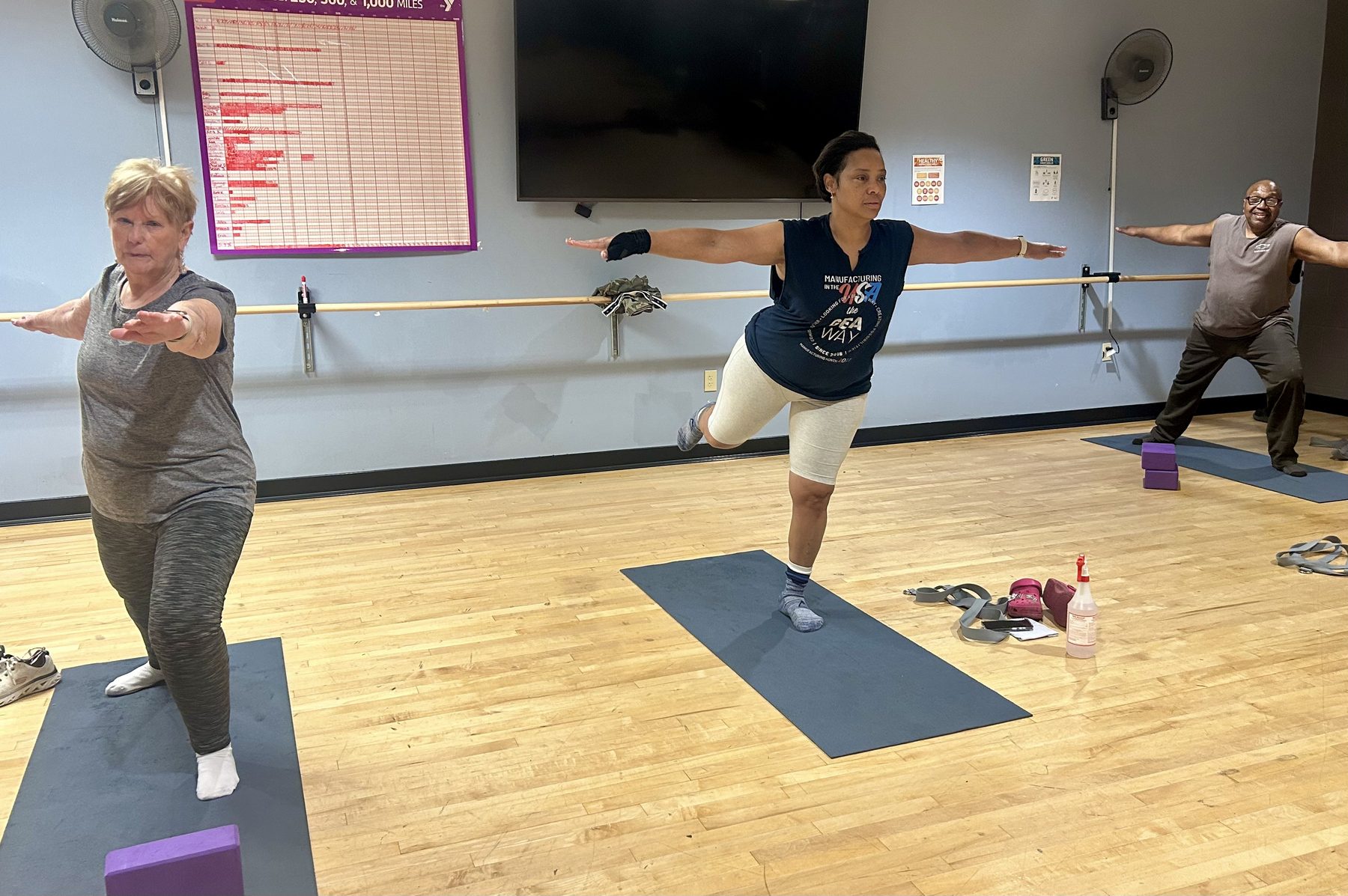 Adults practicing standing balance together in a community yoga class